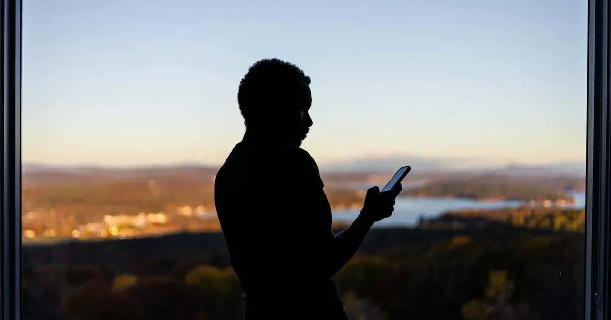 Memorial digital con fotos y recuerdos en la pantalla de un teléfono móvil junto a una lápida