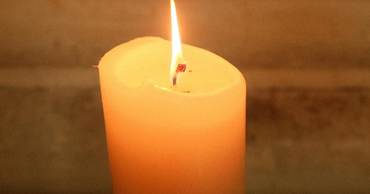 Velas encendidas y flores en un cementerio español durante el Día de Todos los Santos