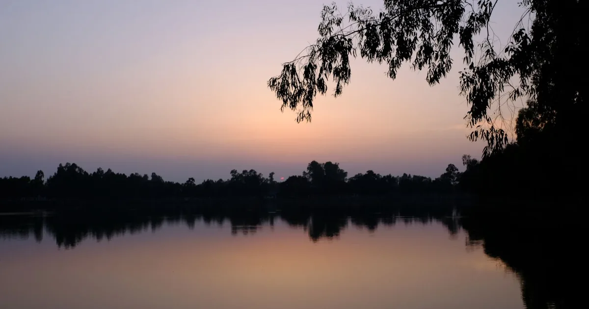 Atardecer sereno sobre un lago en calma, imagen del regreso a casa de un ser querido fallecido lejos de su tierra