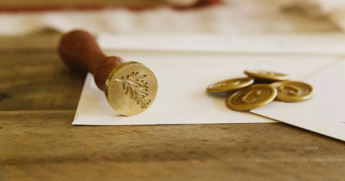 Brass wax-seal stamp with an engraved sprig resting on white envelopes beside gold wax seals: how to find out if a deceased person had life insurance